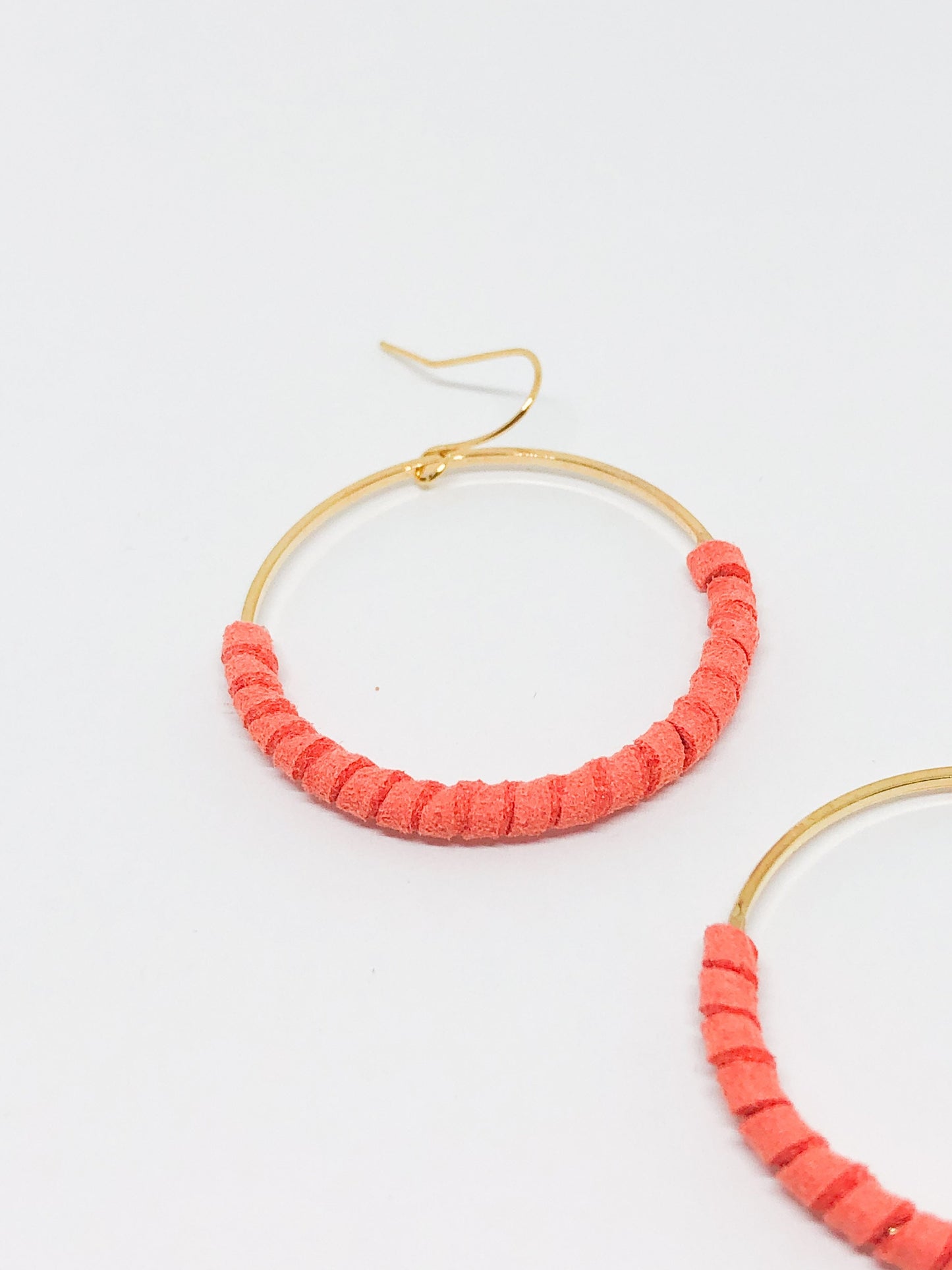 Gold hoop earrings with coral faux suede